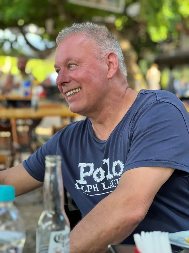 Henk Swama lachend aan een terrastafel