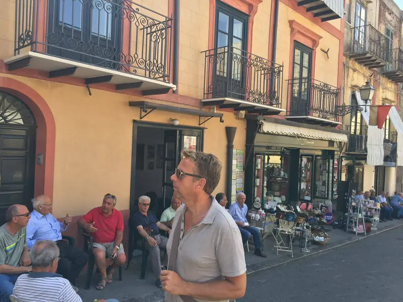 Onno de Vries op een zonnig plein in een Zuid-Europese straat