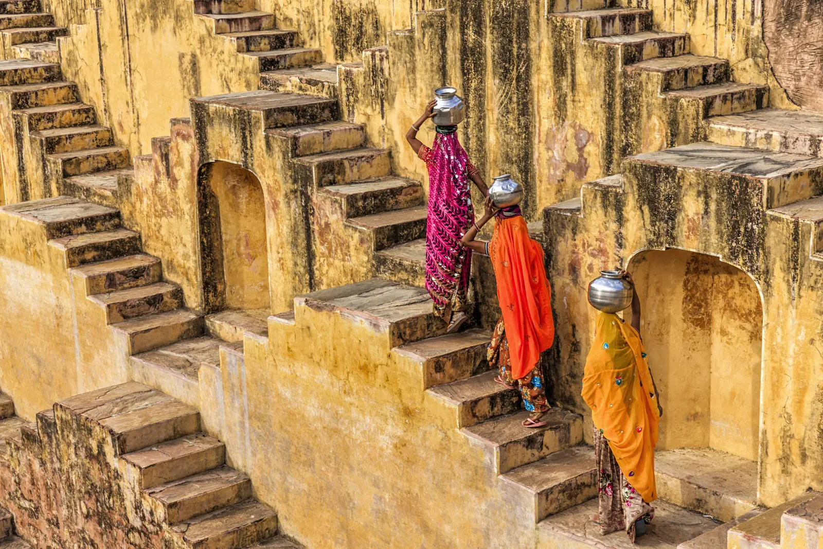 Vrouwen in kleurrijke sari's op de trappen van een trapbron bij Jaipur